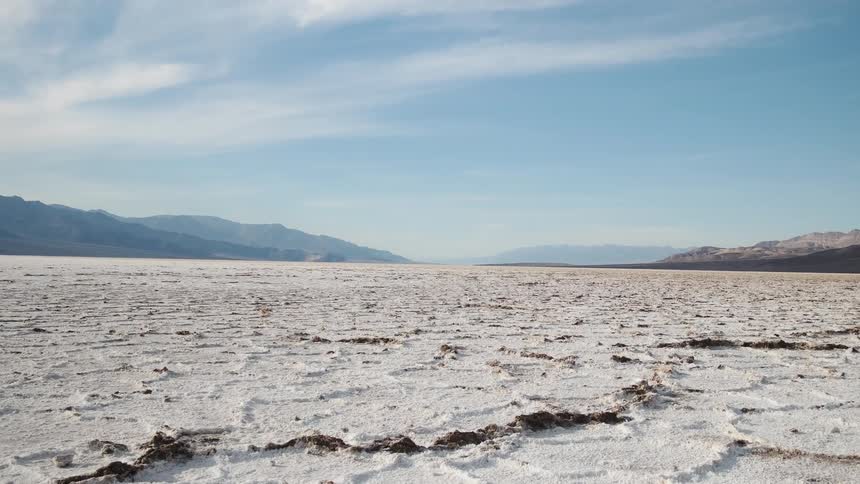 Cracked flat sandy land with hills far away