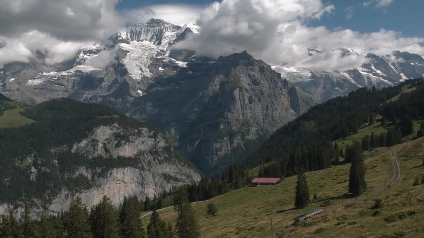 A red train wagon circles around magnificent mountain scenery
