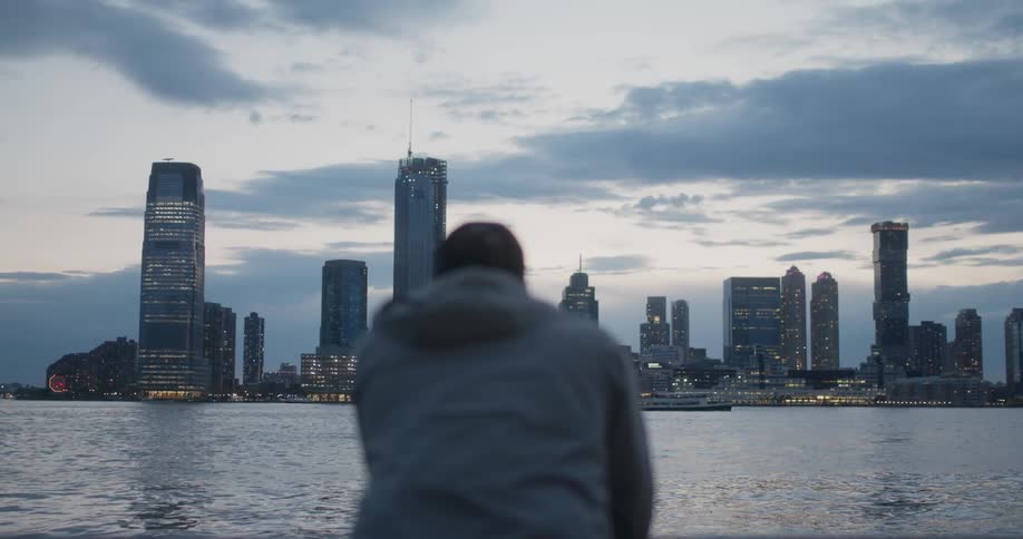 A man leans on the railing looking over the city