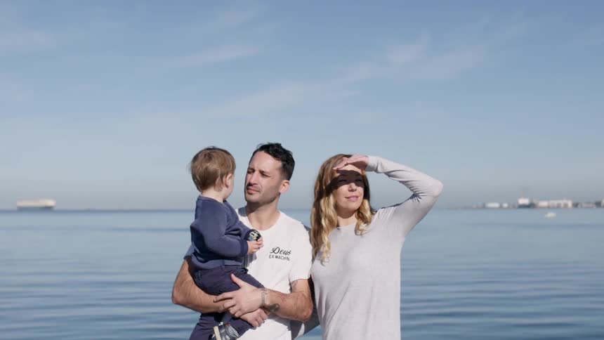 Parents carry a child by the water