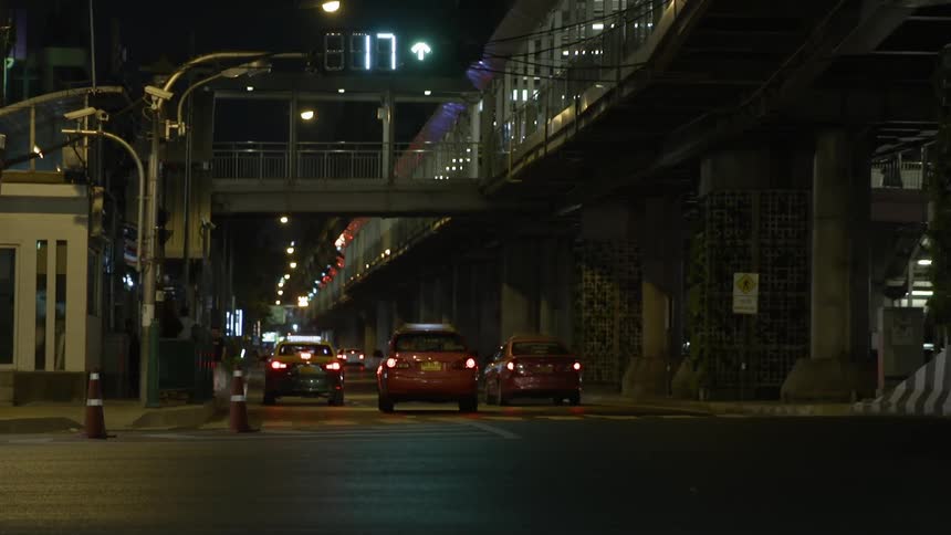 Cars pass under an urban bridge at night