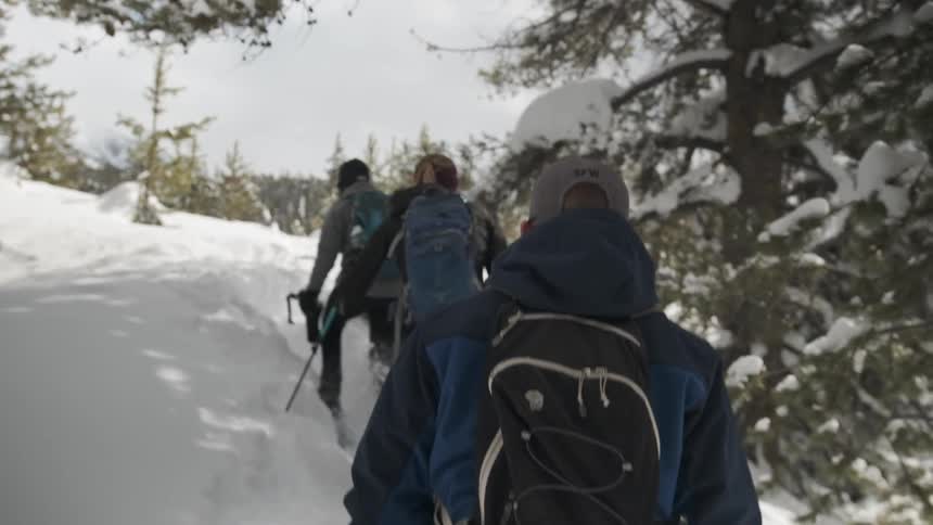A group of people travel through the tall snow