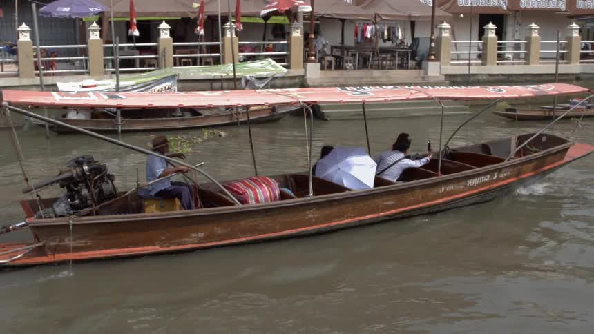 Tourists sit in the front of a longboat as it moves past buildings