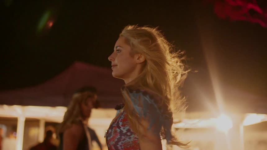 Woman dances outside next to a lit up tent at night