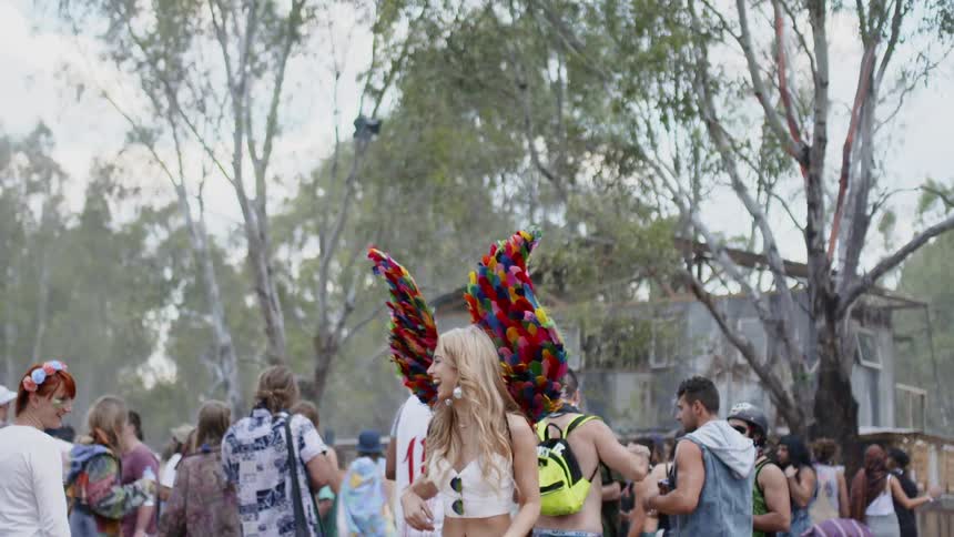 A woman with paper wings walks past a crowd of people smiling