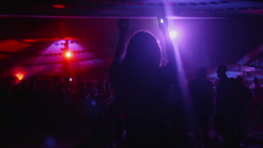 Woman dances in a nightclub with lights flashing