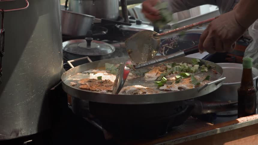 A person is cooking food on a large pan