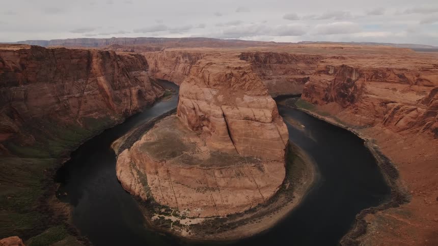 The large canyon has a rock in the center of the water