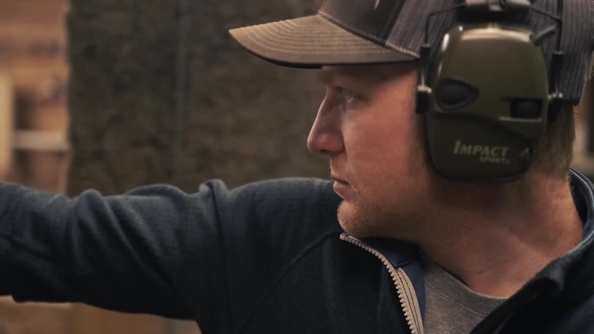 A man aiming a gun at an indoor firing range