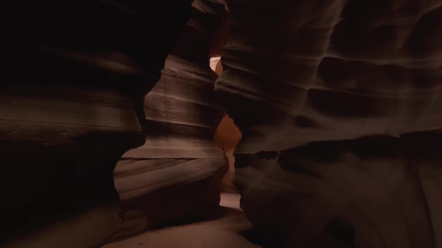 The canyon is dark with sunlight coming in at the end