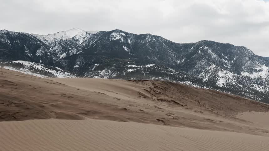 Sand dunes in front of snowy mountains