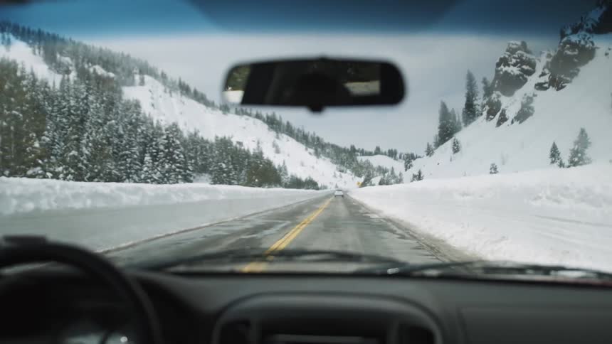 A person is driving on the road with heavy snow on each side
