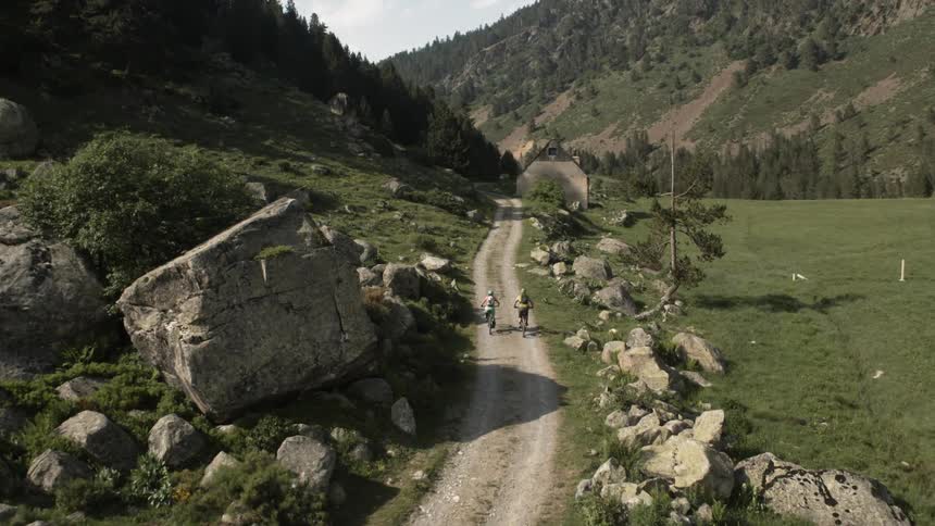 Two people ride their bicycles on the dirt trail
