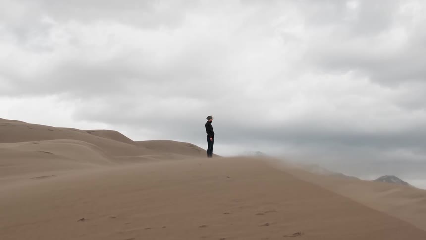 Person standing on top of sand dunes