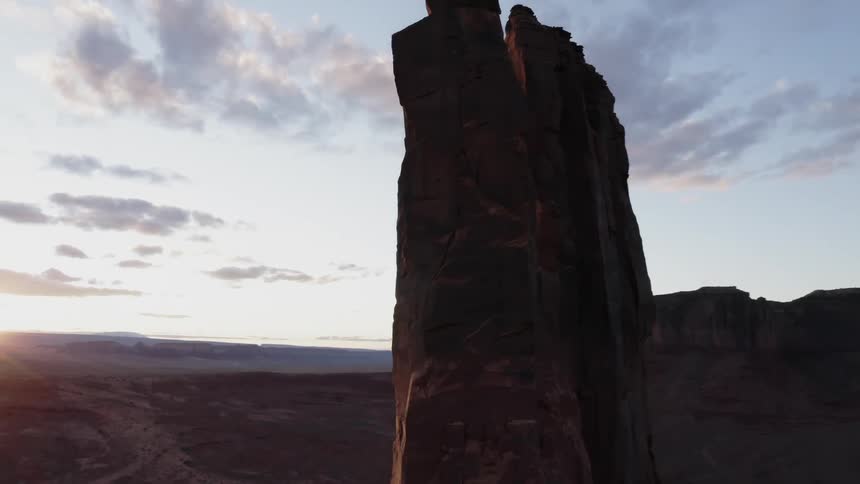 Aerial of massive desert rock formation at sunset