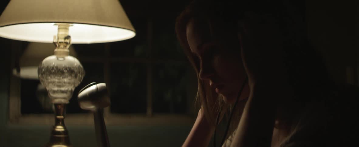 Woman standing by a lamp puts on headphones