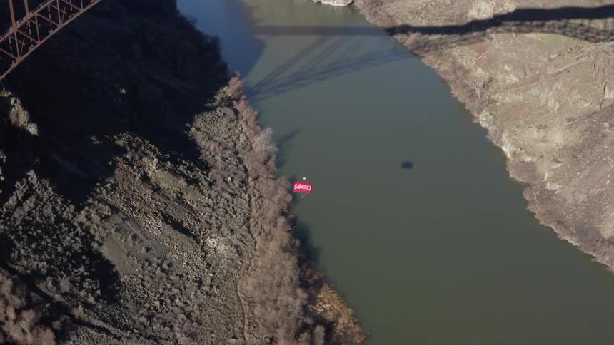 A person paraglides off the tall bridge