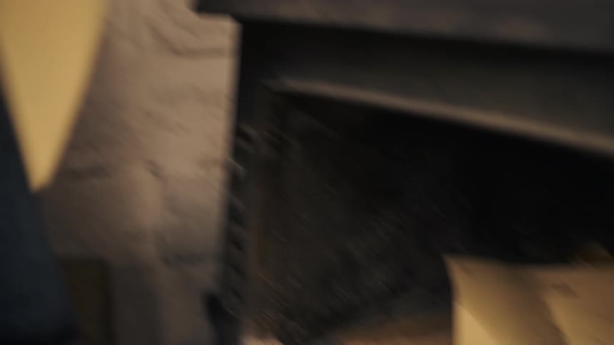 A man places some paper into the stove