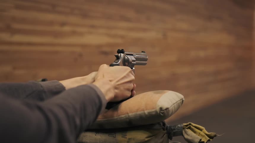 A person is aiming a gun on a couple of pillows