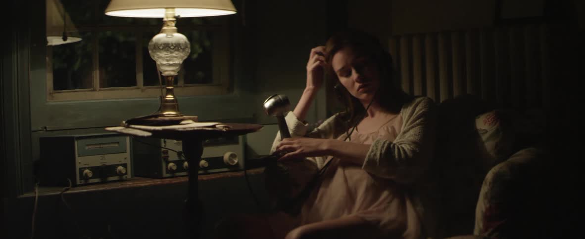 Pregnant woman sitting by a lamp using a microphone