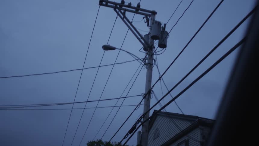 Telephone wires, poles and houses pass by driving down a street