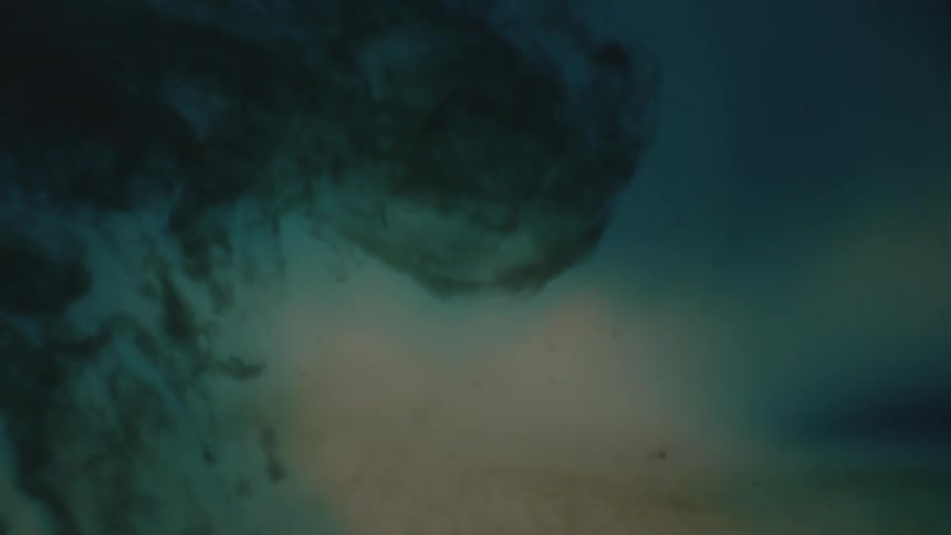 A dark substance disperses in a light blue and white substance