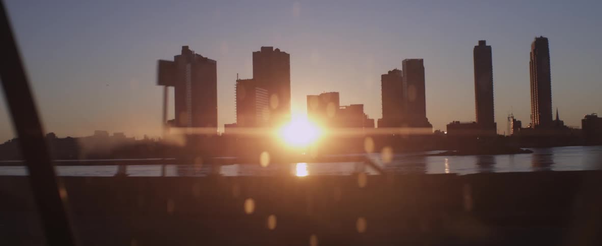 Traffic moving as the sun sets behind a city skyline