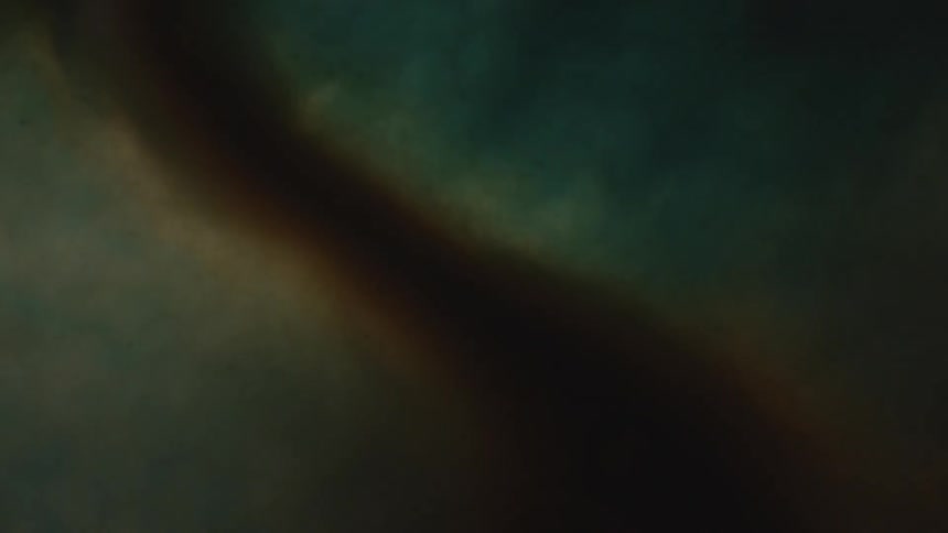 A thick reddish brown substance floats cloud like in a background of bluish white