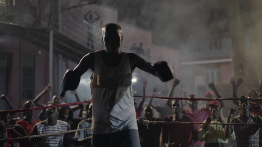 A crowd cheers at an outdoor boxing match