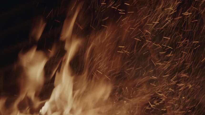 A fire burns wood in the dark