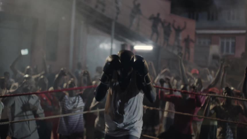 A boxer is pounding his hands together as he prepares to fight outside at night