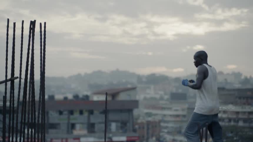 A boxer punches the air on a building rooftop at sunset