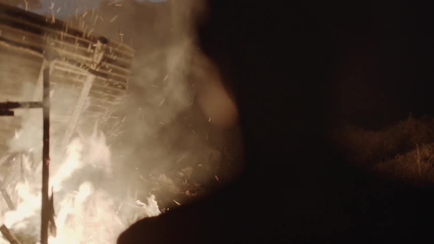 A boy watches a house burn down at night