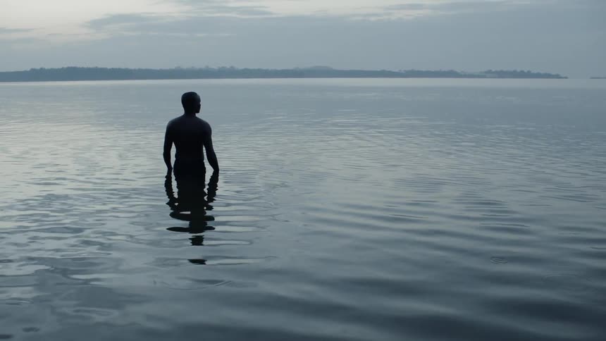 Man stands in a lake of flowing water on a cloudy day