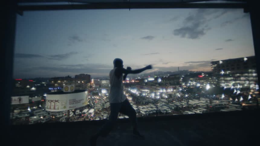 A boxer punches the air on a building rooftop