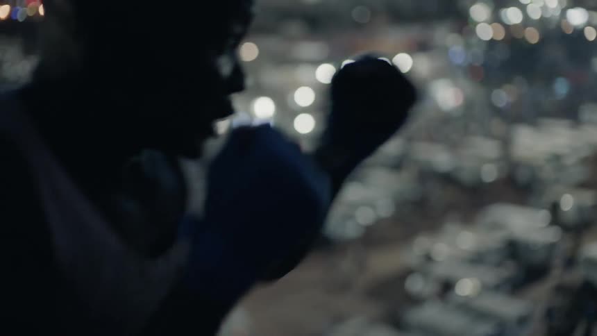 A boxer punches the air on a building rooftop