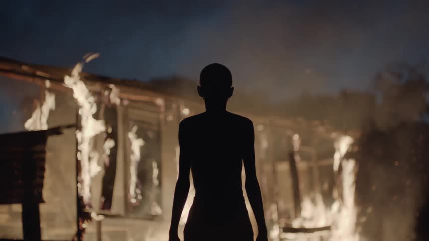 A boy watches a house burn