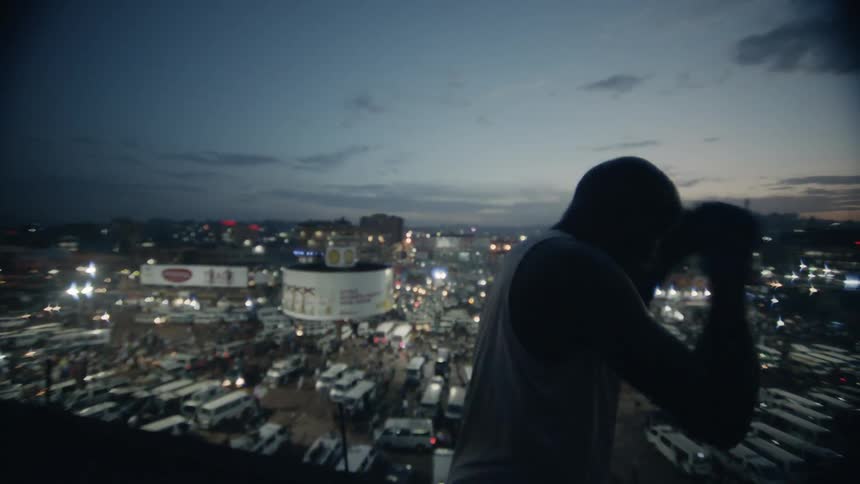 A boxer punches the air on a building rooftop
