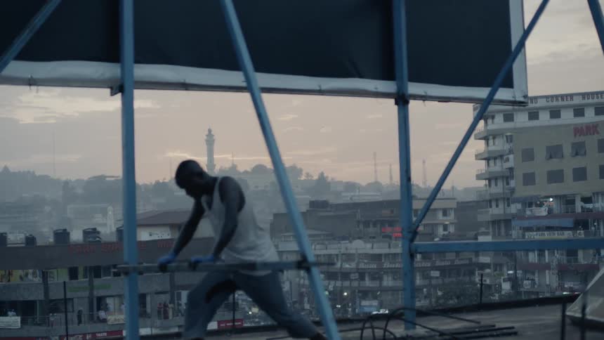 An athlete is stretching and warming up on a rooftop at dusk