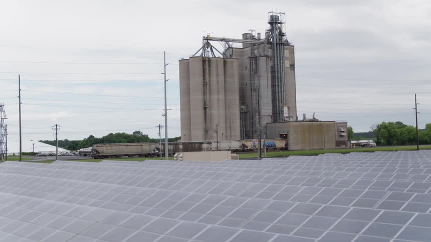 Panels cover crops and large silos stand nearby
