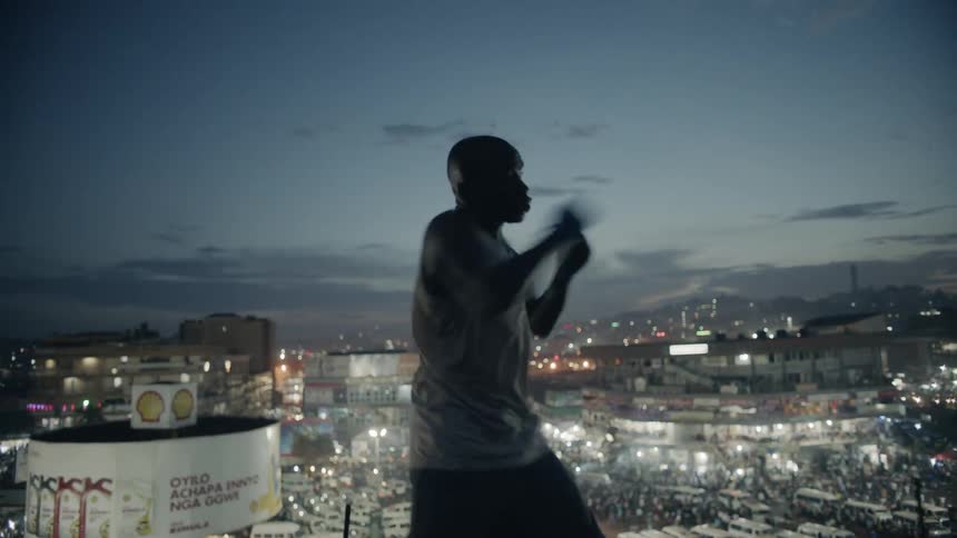 A boxer punches the air in a city at dusk