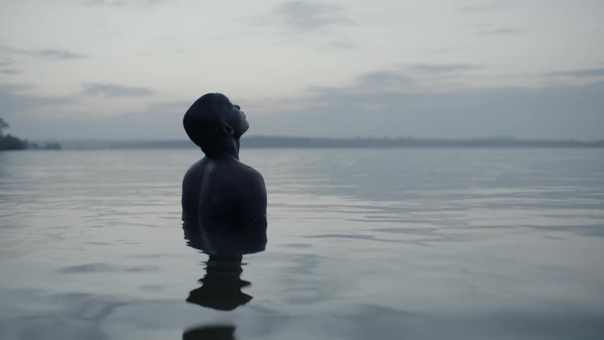 A man stands in a lake at sunset