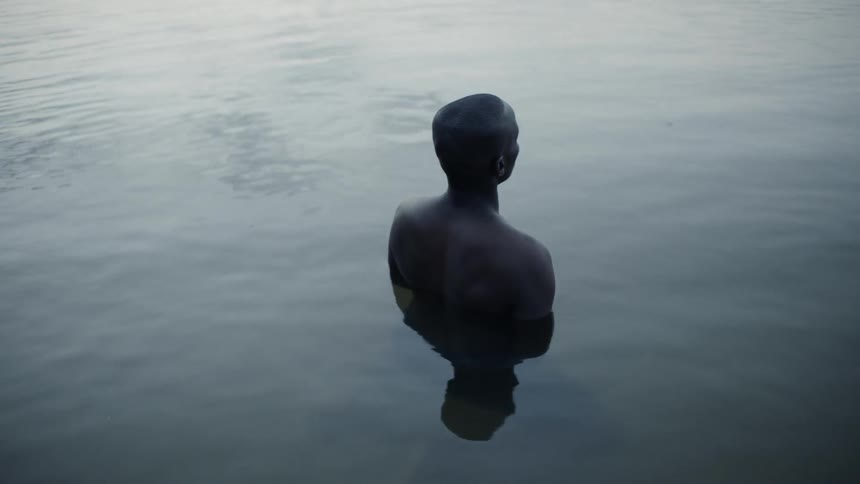 Man stands in a lake at sunset