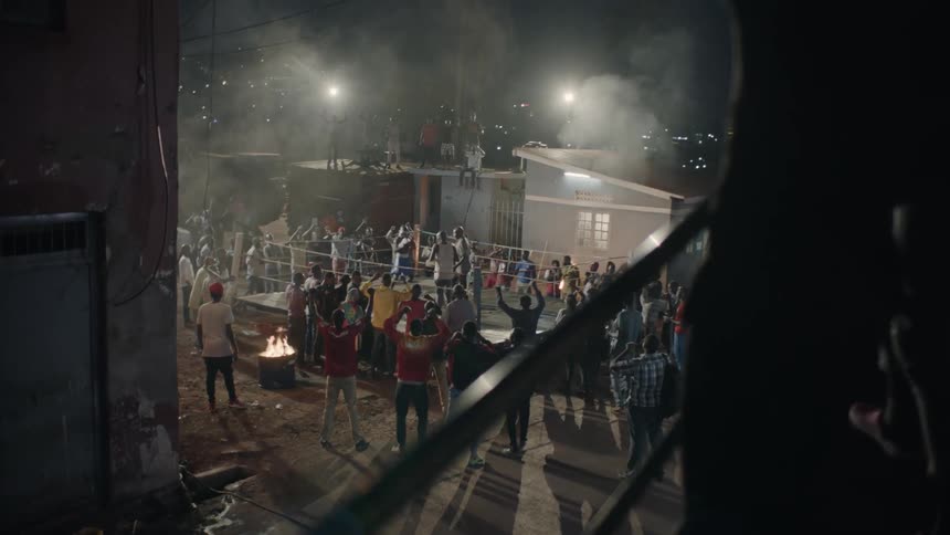 A crowd cheers at an outdoor boxing match
