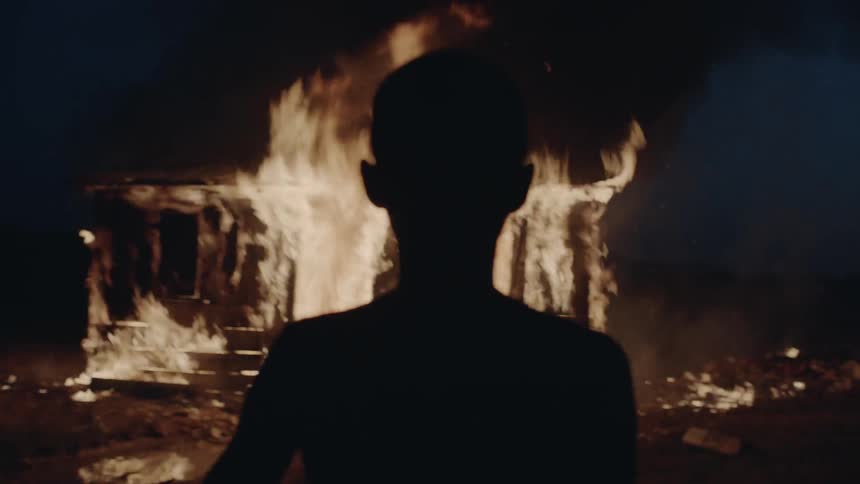 Boy watching a house on fire at night
