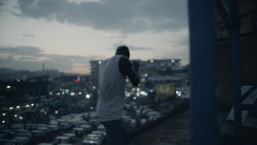 A boxer punches the air on a building rooftop