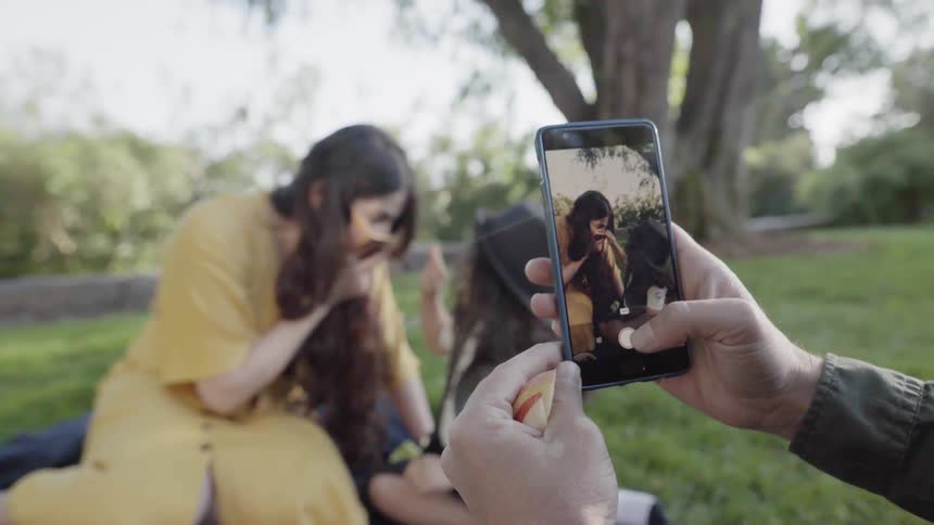 A father taking a photo of a wife and child on smartphone.