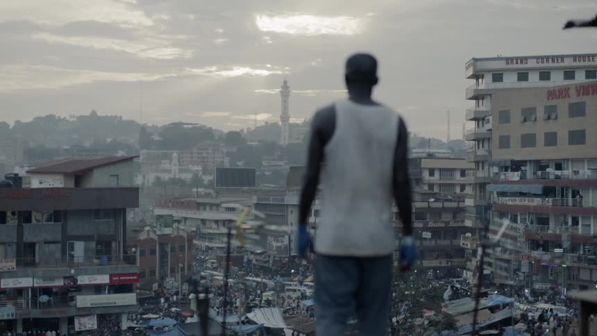 A boxer punches the air on a building rooftop at sunset
