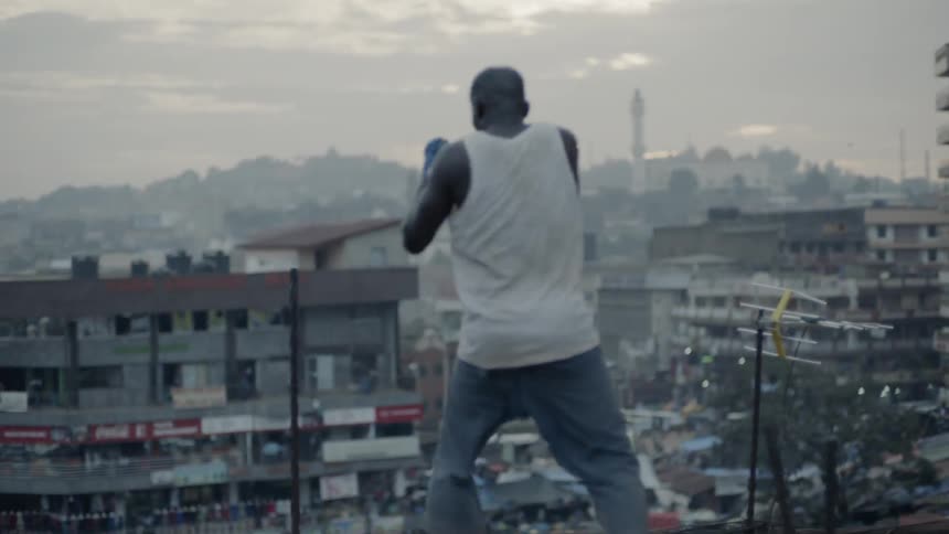 A boxer punches the air on a building rooftop