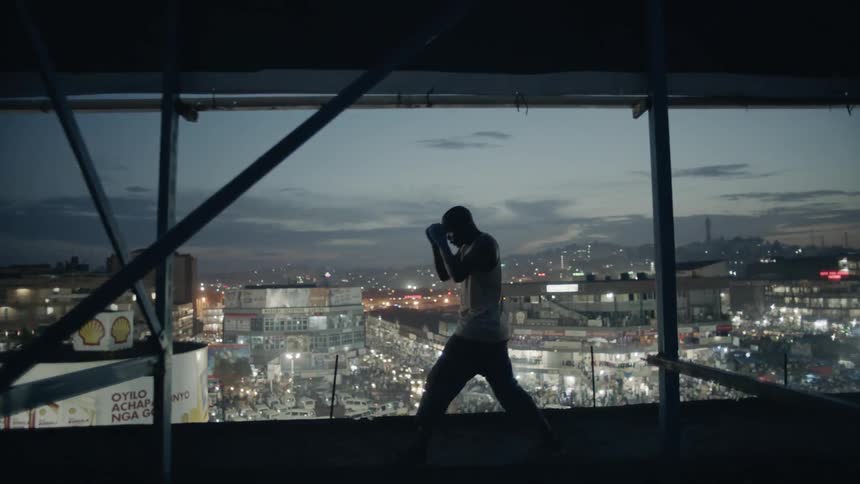 A boxer punches the air on a building rooftop